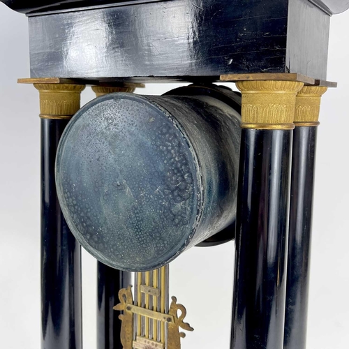 1709 - A French ebonised and ormolu portico clock. 19th century, with gilt capped tapered column supports, ... 