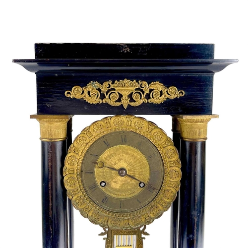 1709 - A French ebonised and ormolu portico clock. 19th century, with gilt capped tapered column supports, ... 