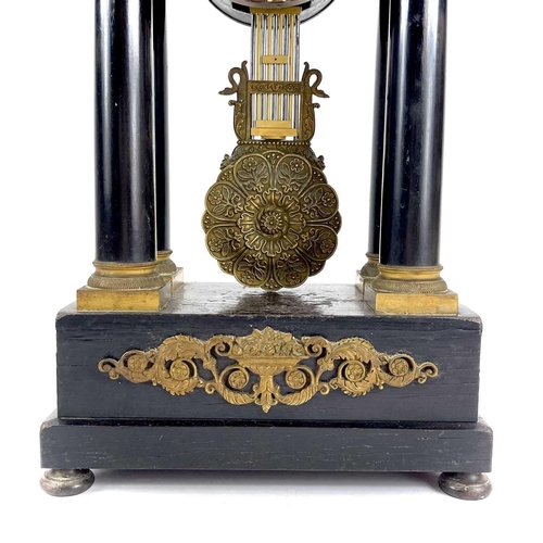 1709 - A French ebonised and ormolu portico clock. 19th century, with gilt capped tapered column supports, ... 