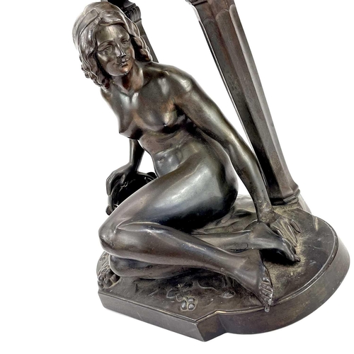 1714 - A French Art Deco spelter mantel timepiece. Modelled as a naked maiden with a tambourine before a fl... 