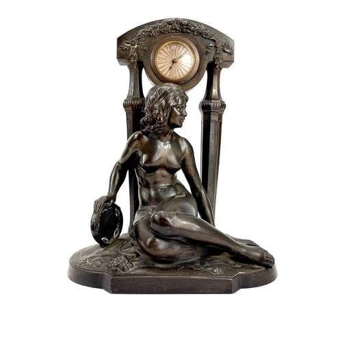 1714 - A French Art Deco spelter mantel timepiece. Modelled as a naked maiden with a tambourine before a fl... 