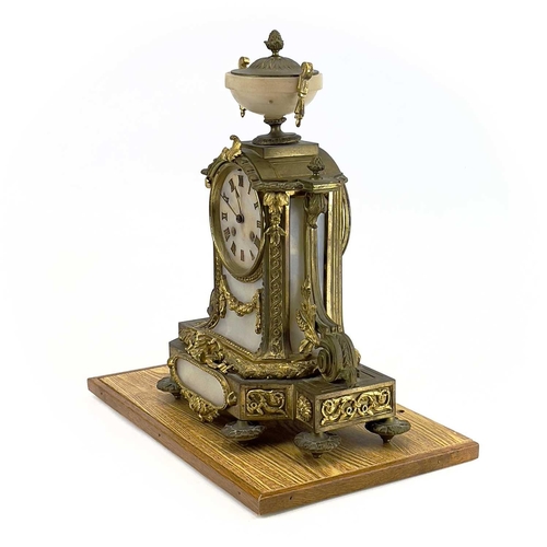 1718 - A French gilt metal and alabaster eight day mantel clock. In the Neo-Classical taste, with urn finia... 