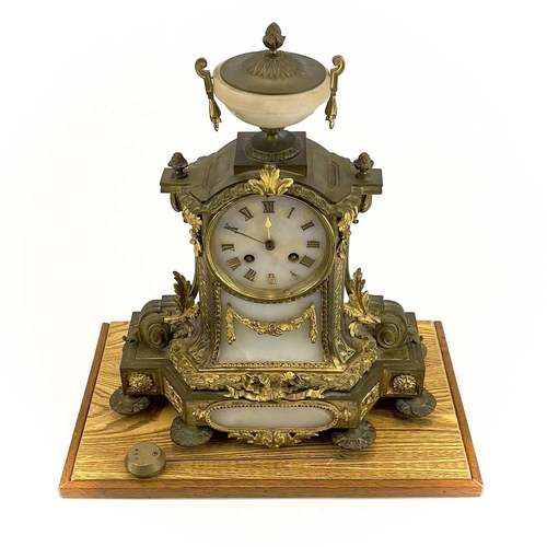 1718 - A French gilt metal and alabaster eight day mantel clock. In the Neo-Classical taste, with urn finia... 