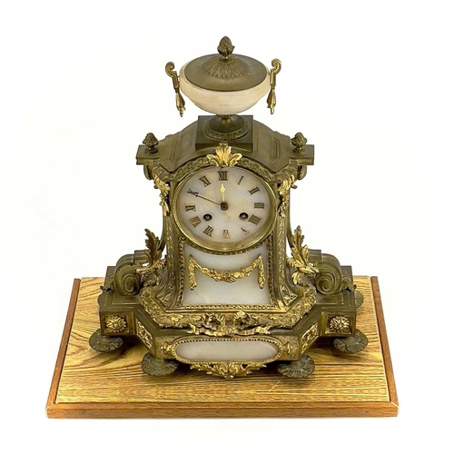 1718 - A French gilt metal and alabaster eight day mantel clock. In the Neo-Classical taste, with urn finia... 