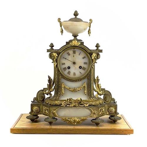 1718 - A French gilt metal and alabaster eight day mantel clock. In the Neo-Classical taste, with urn finia... 