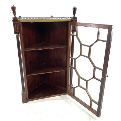 1816 - A Regency mahogany glazed hanging corner cupboard. With pierced brass gallery flanked by turned urns... 