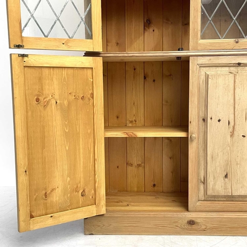 1822 - A pine display cabinet. 20th century, with two glazed doors enclosing shelves and with panel doors b... 