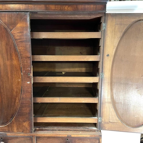 1836 - A George III mahogany linen press. The upper part with two oval panel doors enclosing sliding shelve... 