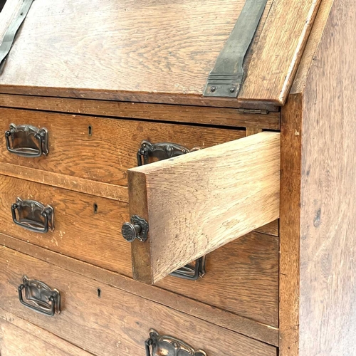 1848 - An Arts and Crafts oak writing bureau. The fall front with repousse copper strap hinges above four d... 