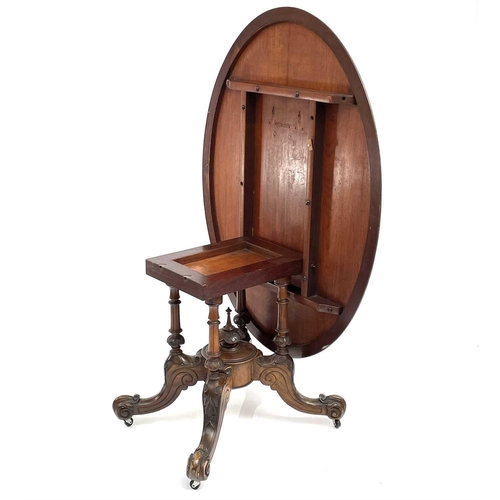 1868 - A mid Victorian walnut oval Loo table. Raised on quadruple turned supports with foliate carved legs ... 