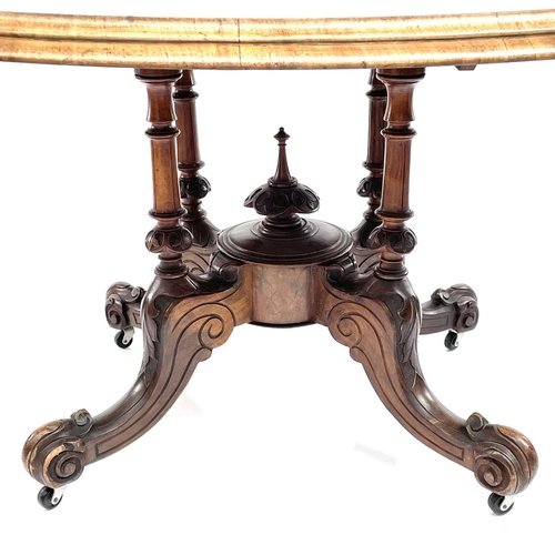 1868 - A mid Victorian walnut oval Loo table. Raised on quadruple turned supports with foliate carved legs ... 