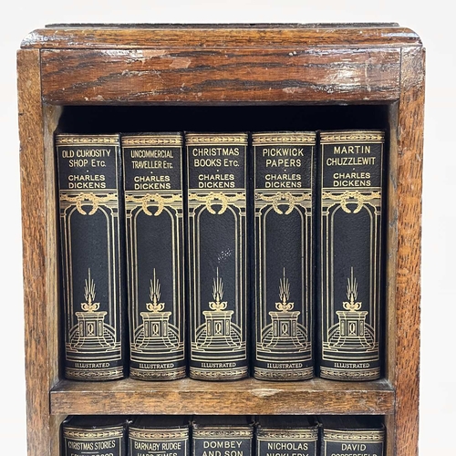 1877 - The works of Charles Dickens contained in a small oak bookcase. Fifteen volumes on three shelves, he... 