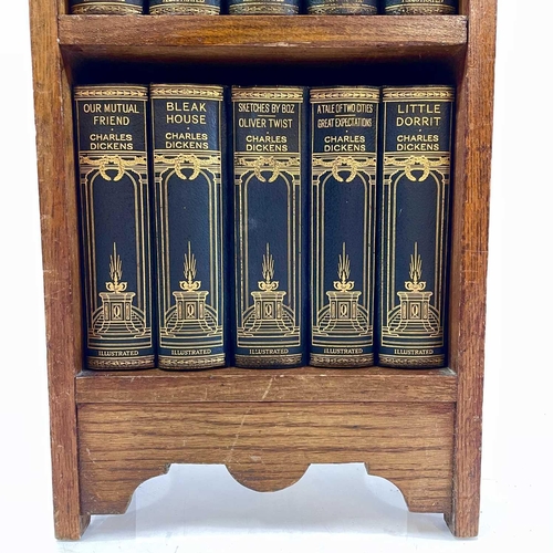 1877 - The works of Charles Dickens contained in a small oak bookcase. Fifteen volumes on three shelves, he... 