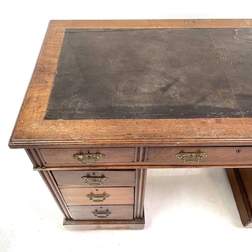 1893 - A late Victorian walnut kneehole desk. With an arrangement of nine drawers on a plinth base and cast... 