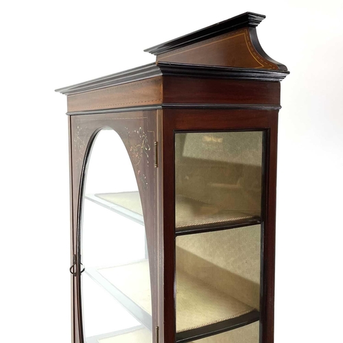 1920 - An Edwardian mahogany inlaid and painted display cabinet. With an oval glazed door enclosing three s... 