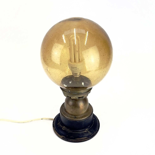 258 - An Art Deco table lamp. With amber glass globular shade, the brass base raised on an ebonised wood s... 