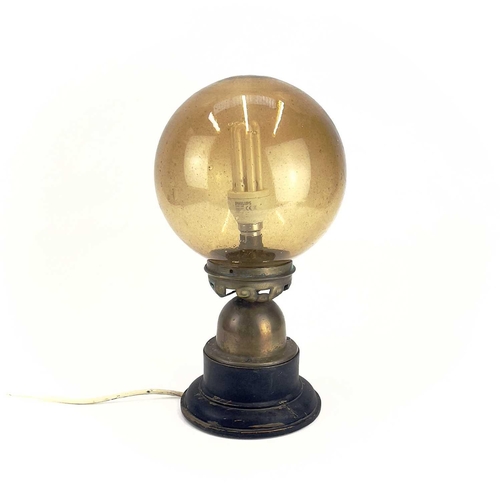 258 - An Art Deco table lamp. With amber glass globular shade, the brass base raised on an ebonised wood s... 