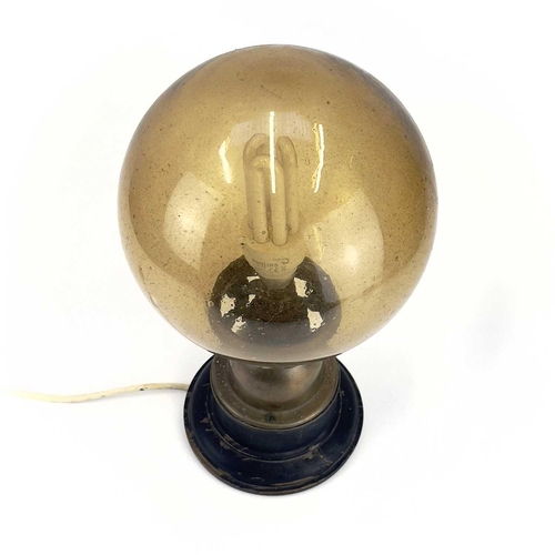 258 - An Art Deco table lamp. With amber glass globular shade, the brass base raised on an ebonised wood s... 