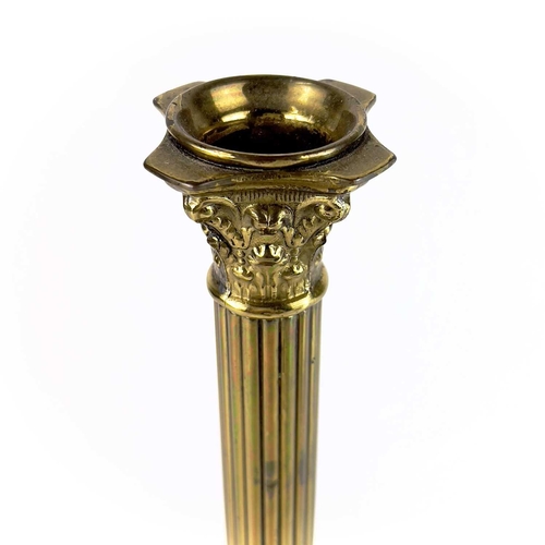 260 - A pair of brass Corinthian column candlesticks. Topped with acanthus scrolls on a stepped plinth bas... 