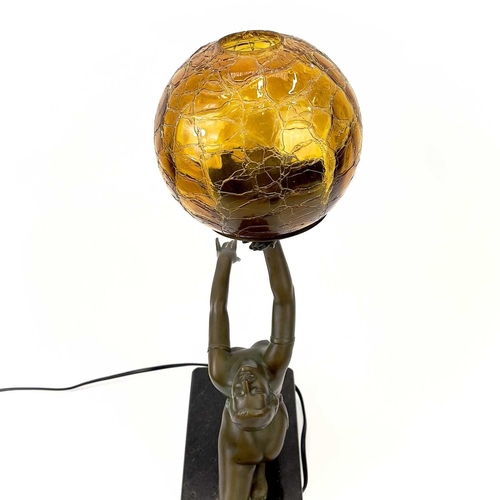 273 - An Art Deco style table lamp. Modelled as a female figure holding an amber glass ball, on a rectangu... 