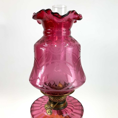 333 - A Victorian cranberry glass oil lamp, With an etched cranberry shade, on a brass base, height 62cm.