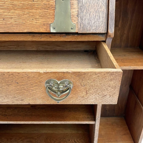 401 - An Arts and Crafts oak bureau cabinet. Circa 1900, the central fall with brass hinges and handle pie... 