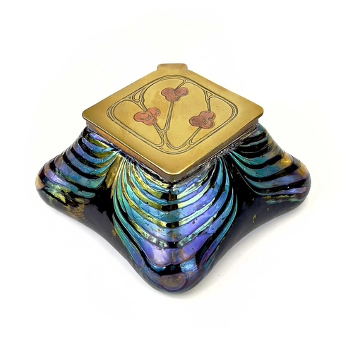 415 - An iridescent glass inkwell, probably Loetz. The lozenge shape brass cover inlaid in copper with ber... 