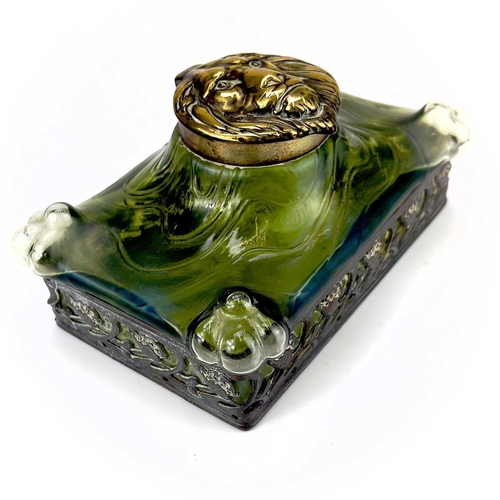 419 - A remarkable iridescent glass inkwell, probably Loetz. The brass cover embossed with a lion mask, th... 