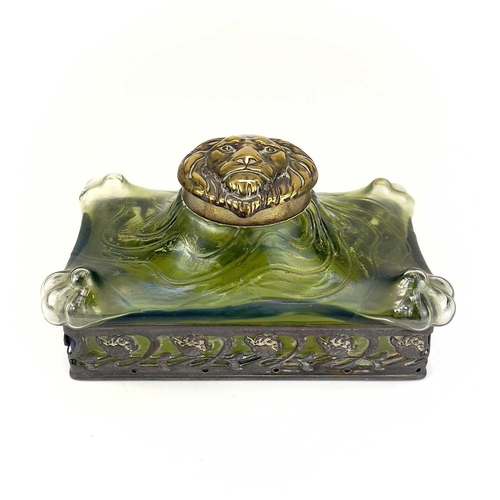 419 - A remarkable iridescent glass inkwell, probably Loetz. The brass cover embossed with a lion mask, th... 