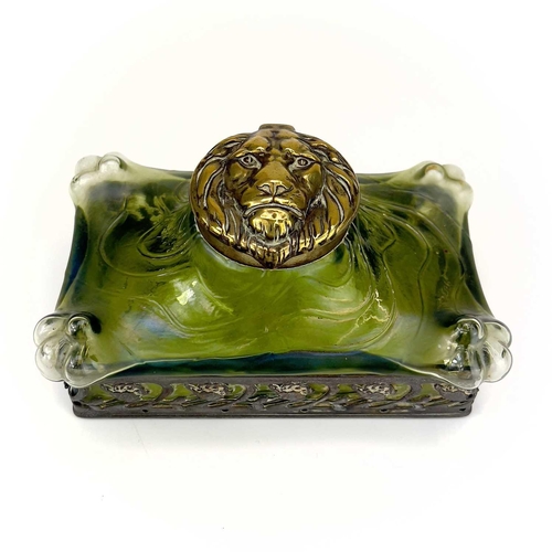 419 - A remarkable iridescent glass inkwell, probably Loetz. The brass cover embossed with a lion mask, th... 