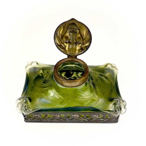 419 - A remarkable iridescent glass inkwell, probably Loetz. The brass cover embossed with a lion mask, th... 