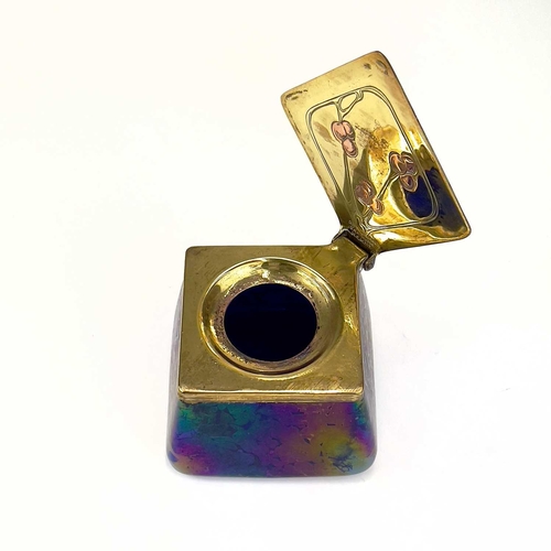 422 - A Loetz type iridescent glass inkwell. Of lozenge shape, the brass cover with copper inset fruiting ... 