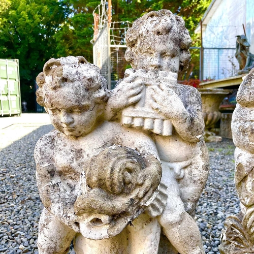 605 - A reconstituted stone fountain, modelled as putti playing pan pipes. Height 55cm together with anoth... 