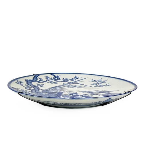 811 - A Japanese Arita blue and white charger. Circa 1900, painted with a pheasant beside a prunus tree an... 