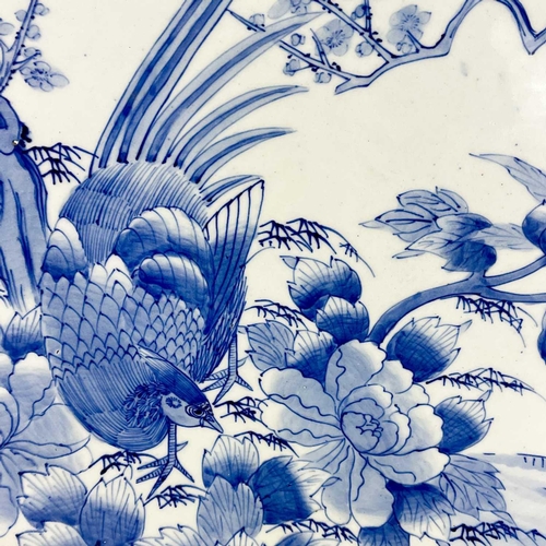 811 - A Japanese Arita blue and white charger. Circa 1900, painted with a pheasant beside a prunus tree an... 