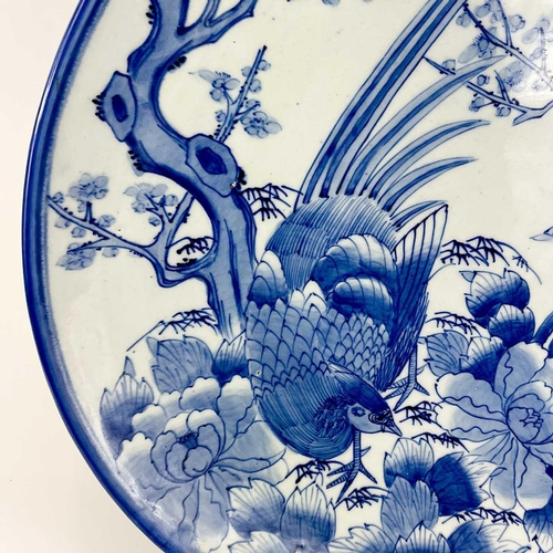 811 - A Japanese Arita blue and white charger. Circa 1900, painted with a pheasant beside a prunus tree an... 