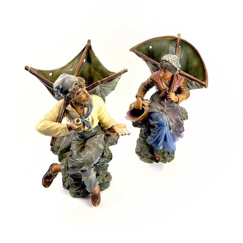 814 - A pair of continental majolica wall pockets Moulded as a seated fisherfolk holding nets, impressed m... 