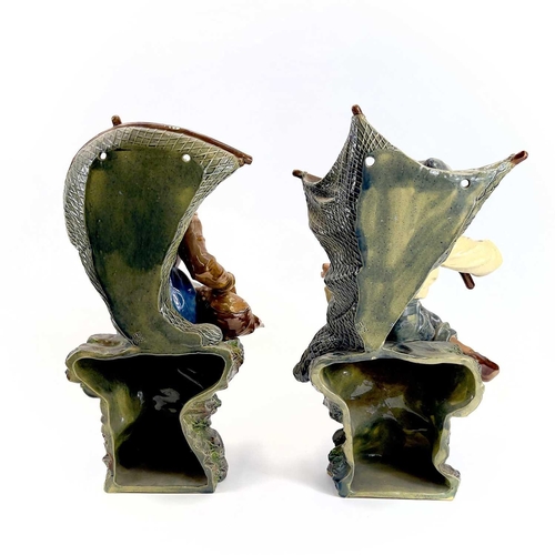 814 - A pair of continental majolica wall pockets Moulded as a seated fisherfolk holding nets, impressed m... 