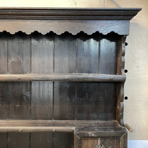 5 - A late Victorian oak dresser. The plate rack fitted two carved cupboard doors, the base with two dra... 