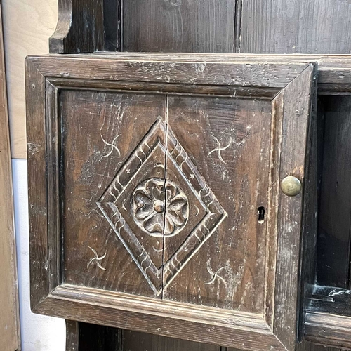 5 - A late Victorian oak dresser. The plate rack fitted two carved cupboard doors, the base with two dra... 