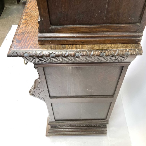 33 - A Victorian oak bookcase cabinet. The upper part with open adjustable shelves with lion mask ring mo... 