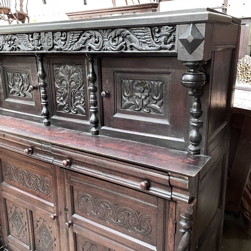 50 - An oak court cupboard, partly 17th century. The carved frieze with initials C.R.B above two doors fl... 