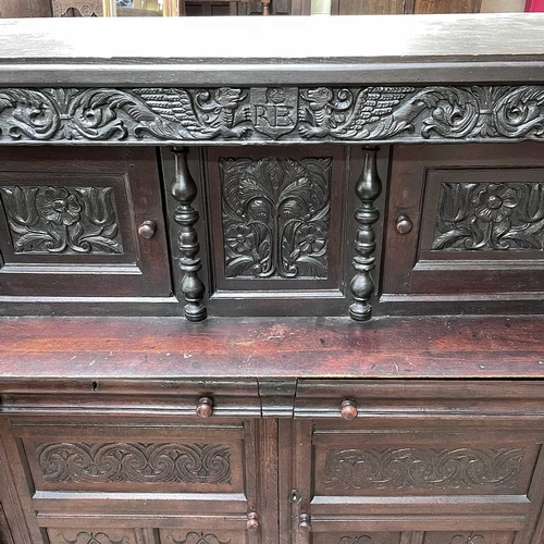 50 - An oak court cupboard, partly 17th century. The carved frieze with initials C.R.B above two doors fl... 