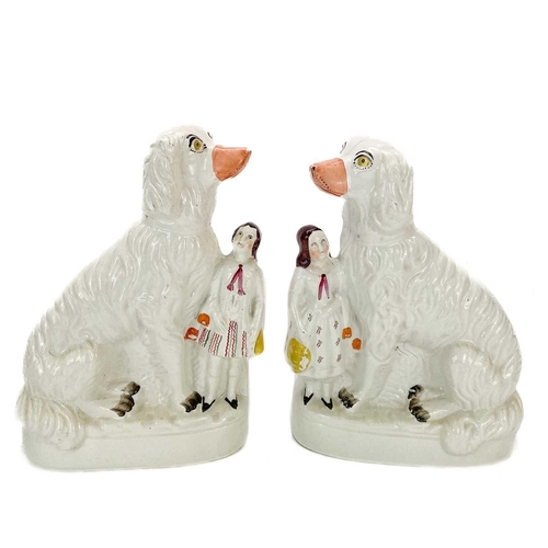 113 - A pair of Victorian Staffordshire figures of oversized spaniels. Seated beside diminutive figures wi... 