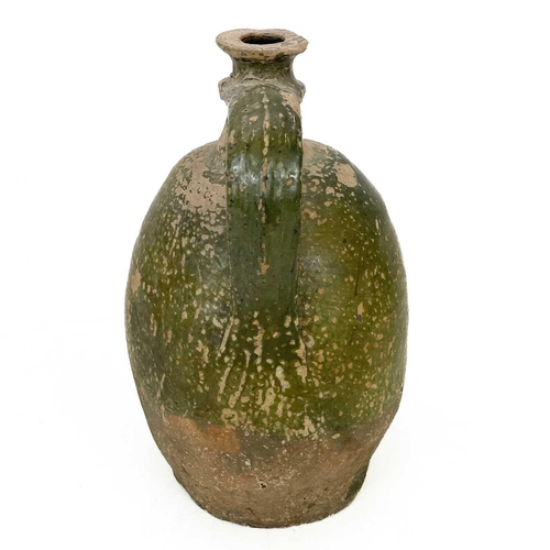 128 - An early 19th century large French pottery oil jug. With green glaze and sing handle, height 32cm.