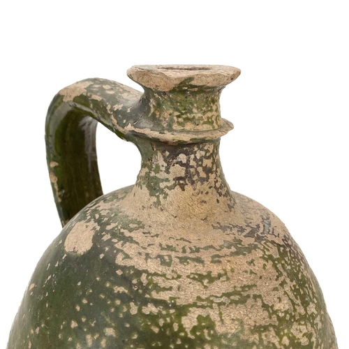 128 - An early 19th century large French pottery oil jug. With green glaze and sing handle, height 32cm.