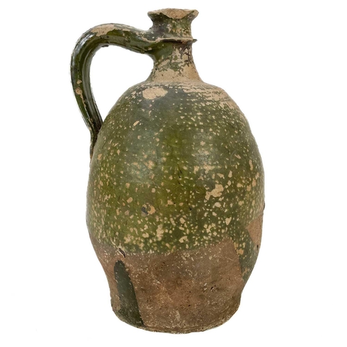 128 - An early 19th century large French pottery oil jug. With green glaze and sing handle, height 32cm.