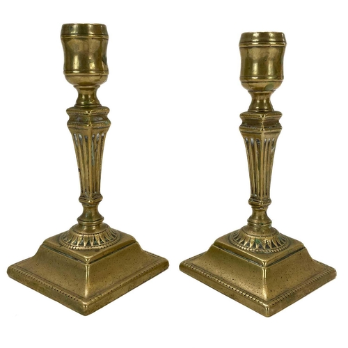 138 - A pair of Georgian brass candlesticks. With square fluted columns on square bases, height 16.5cm.Som... 