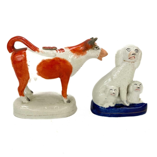 153 - A Staffordshire pottery cow creamer and cover. With tan and white markings on an oval base, length 1... 