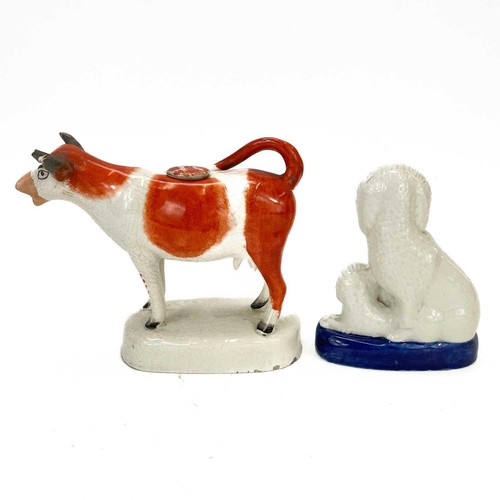 153 - A Staffordshire pottery cow creamer and cover. With tan and white markings on an oval base, length 1... 